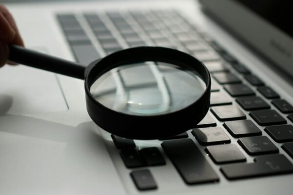 Magnifying glass near gray laptop computer