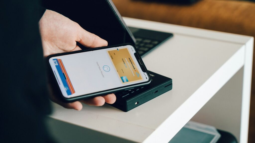 A person holding a smartphone over a card reader for contactless payment