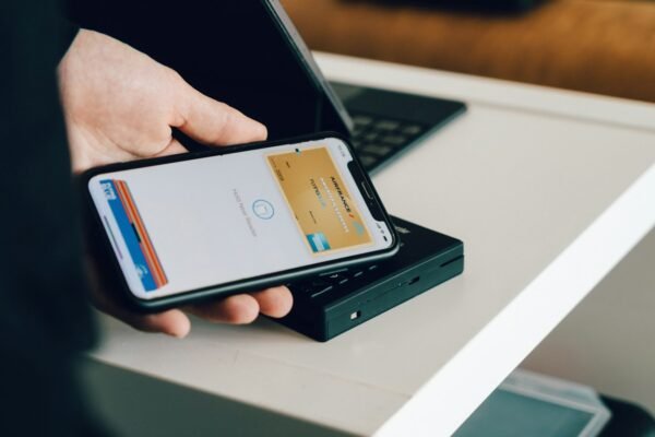 A person holding a smartphone over a card reader for contactless payment