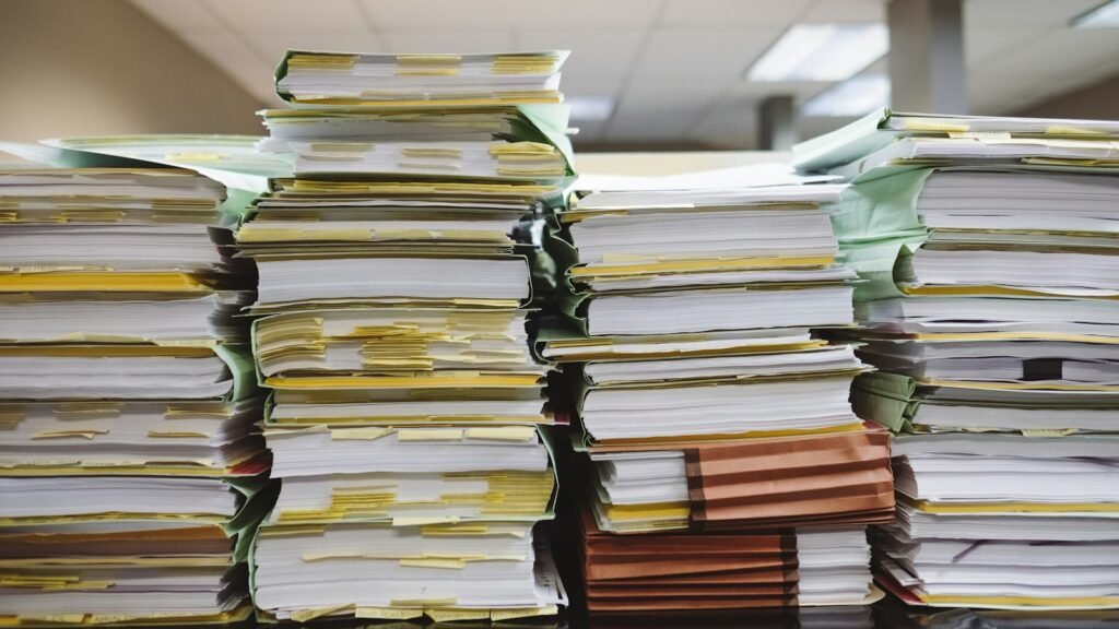 Outgrown spreadsheets: stacks of paper documents and file folders