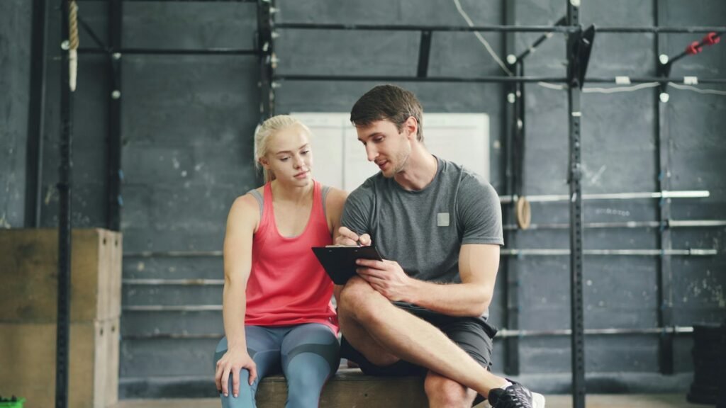Online booking systems in use: trainer reviewing progress with a client on a tablet