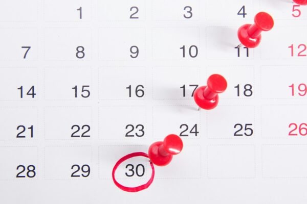 A calendar with red push buttons pinned to it