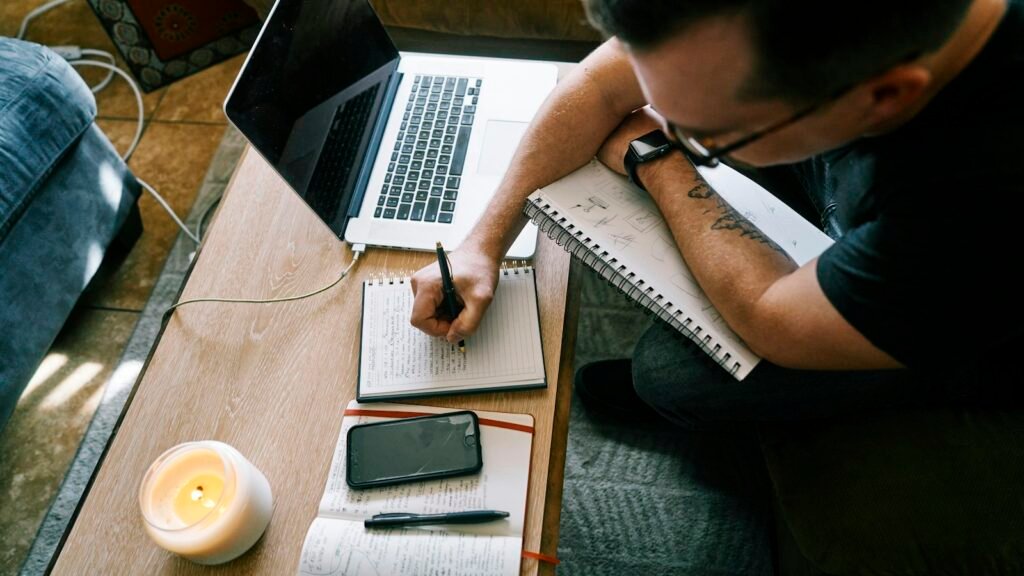 Blog plan being written: man in a black t-shirt writing on white paper