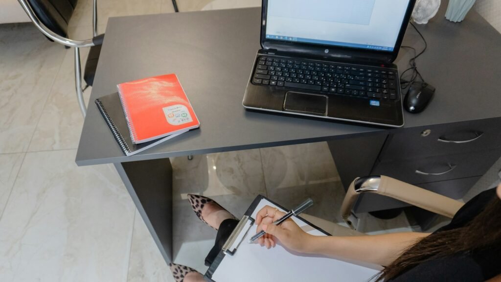 Writing a website brief on a clipboard at a desk with a laptop