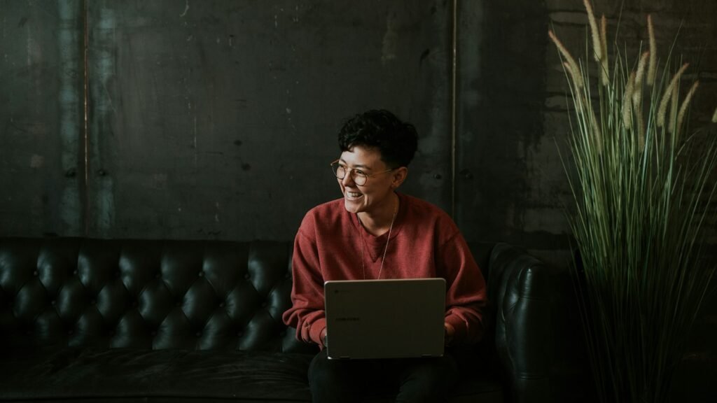 Website accessibility check: smiling man using a laptop on a black leather sofa