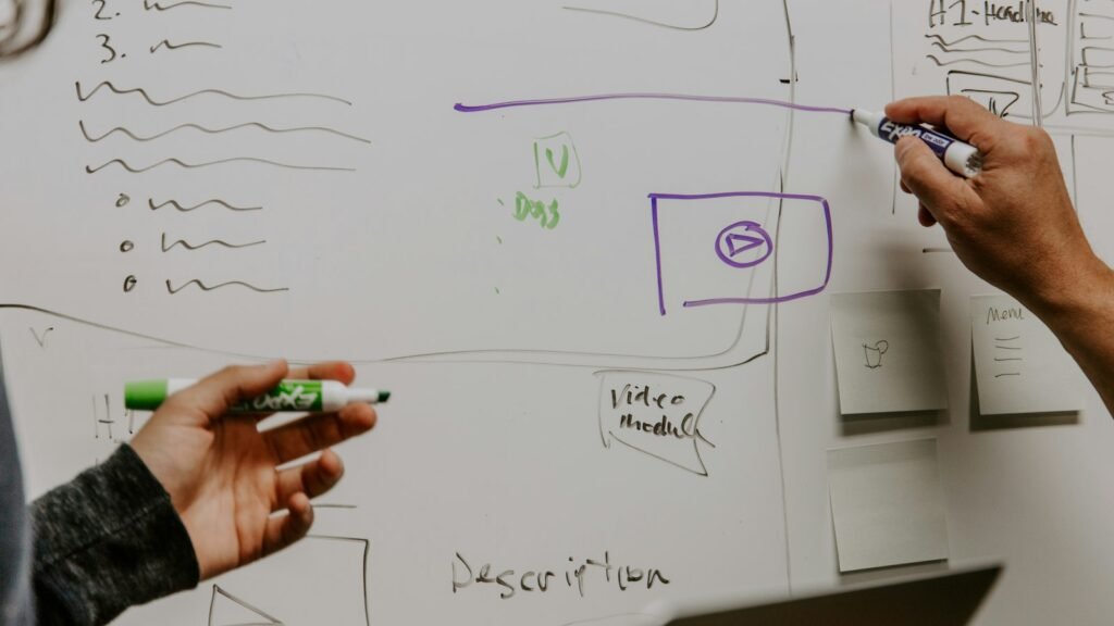 Website or web app planning: two people sketching ideas on a whiteboard