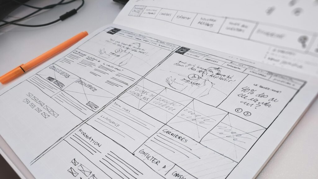 Website redesign wireframe drawn on paper with an orange pen on a desk