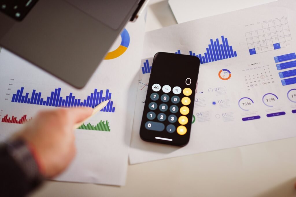Calculator on a desk next to a laptop, used to work out custom software cost