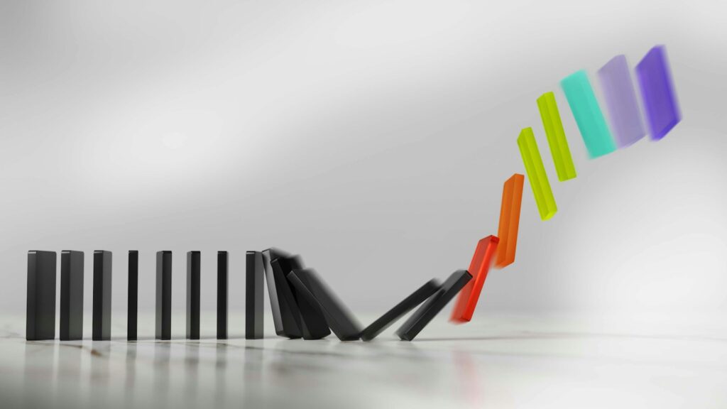 A line of colourful dominoes toppling one after another in a chain reaction