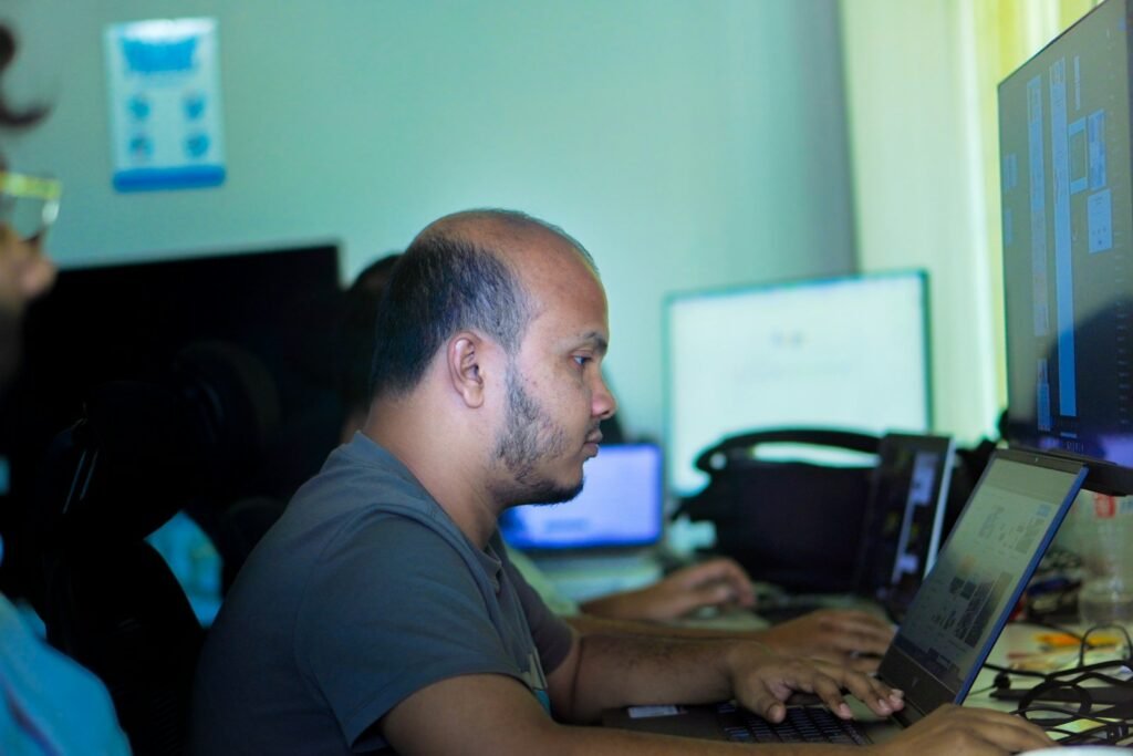 A developer typing on a laptop in a shared office during custom software development work