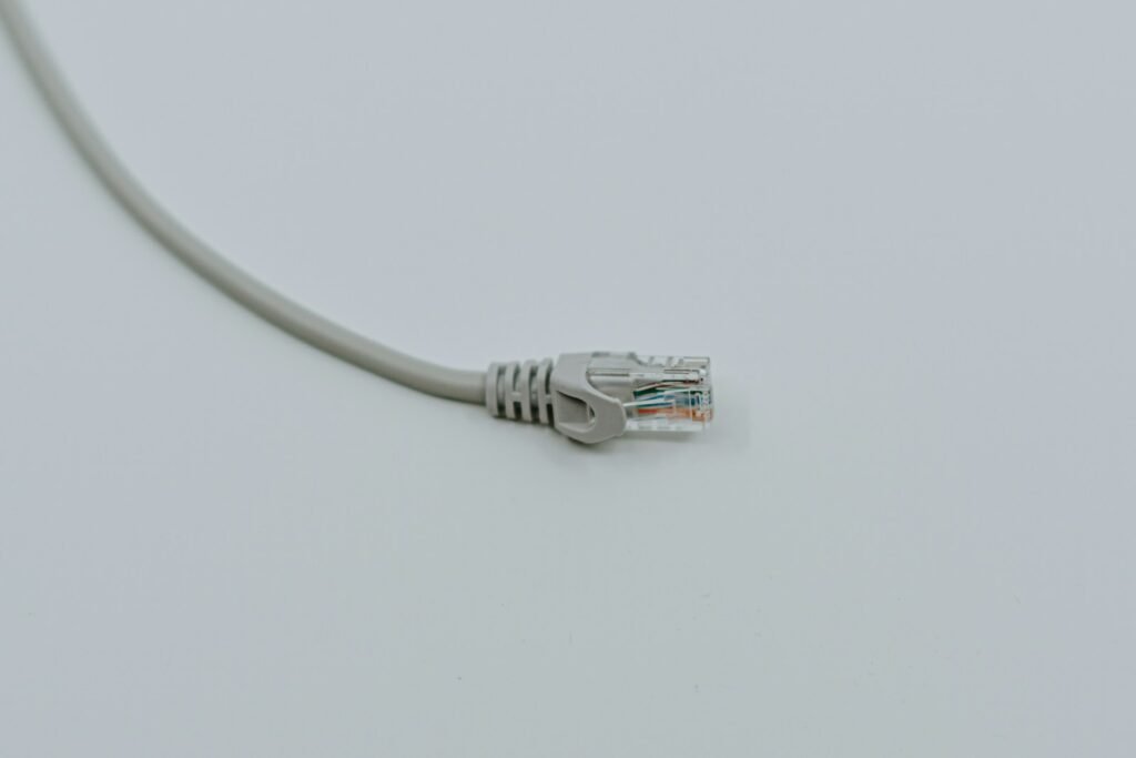 A grey ethernet cable with its connector lying on a plain white surface