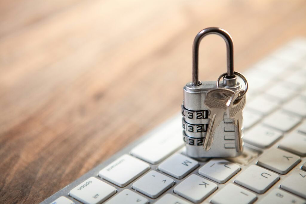 A combination padlock with a pair of keys resting on a white computer keyboard