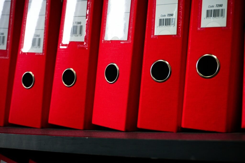 Red lever arch files neatly arranged side by side on an office shelf