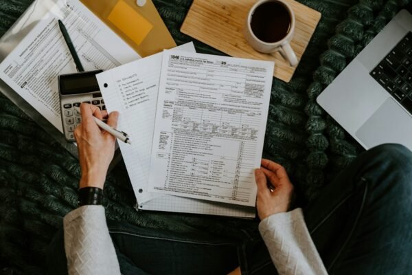 Person reviewing paper records with a calculator and laptop before moving to Making Tax Digital